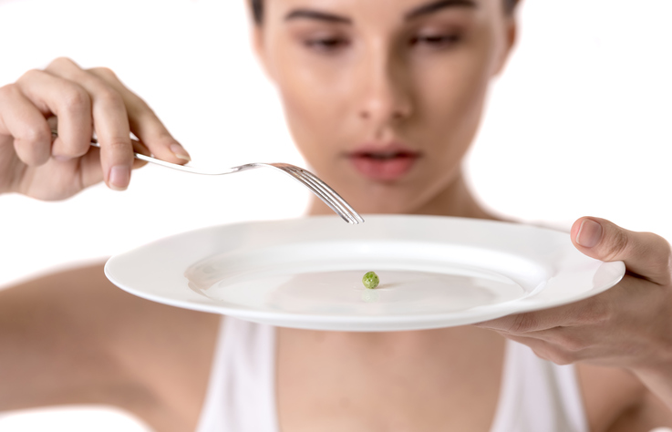 Woman with peas on her plate, restricts food